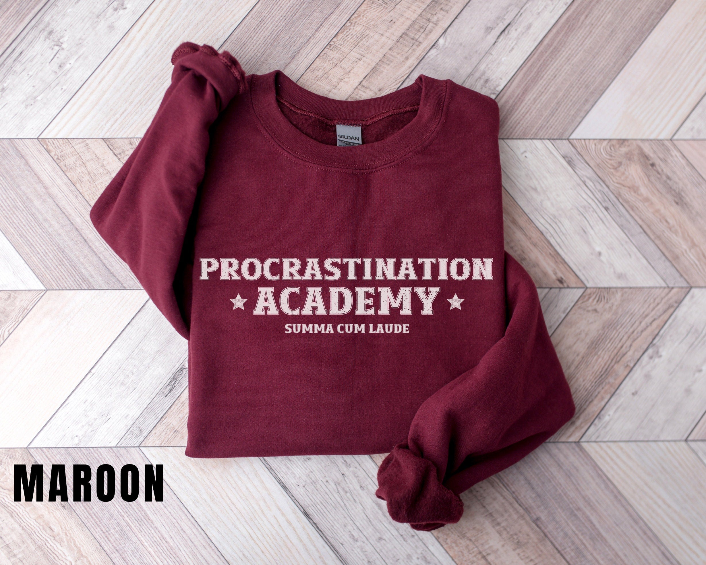 a maroon sweatshirt with the words procrastination academy on it