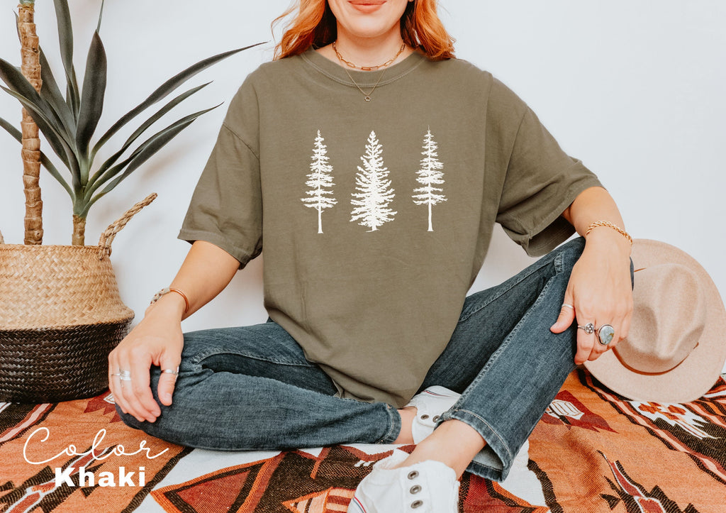 a woman sitting on the floor wearing a t - shirt with trees on it