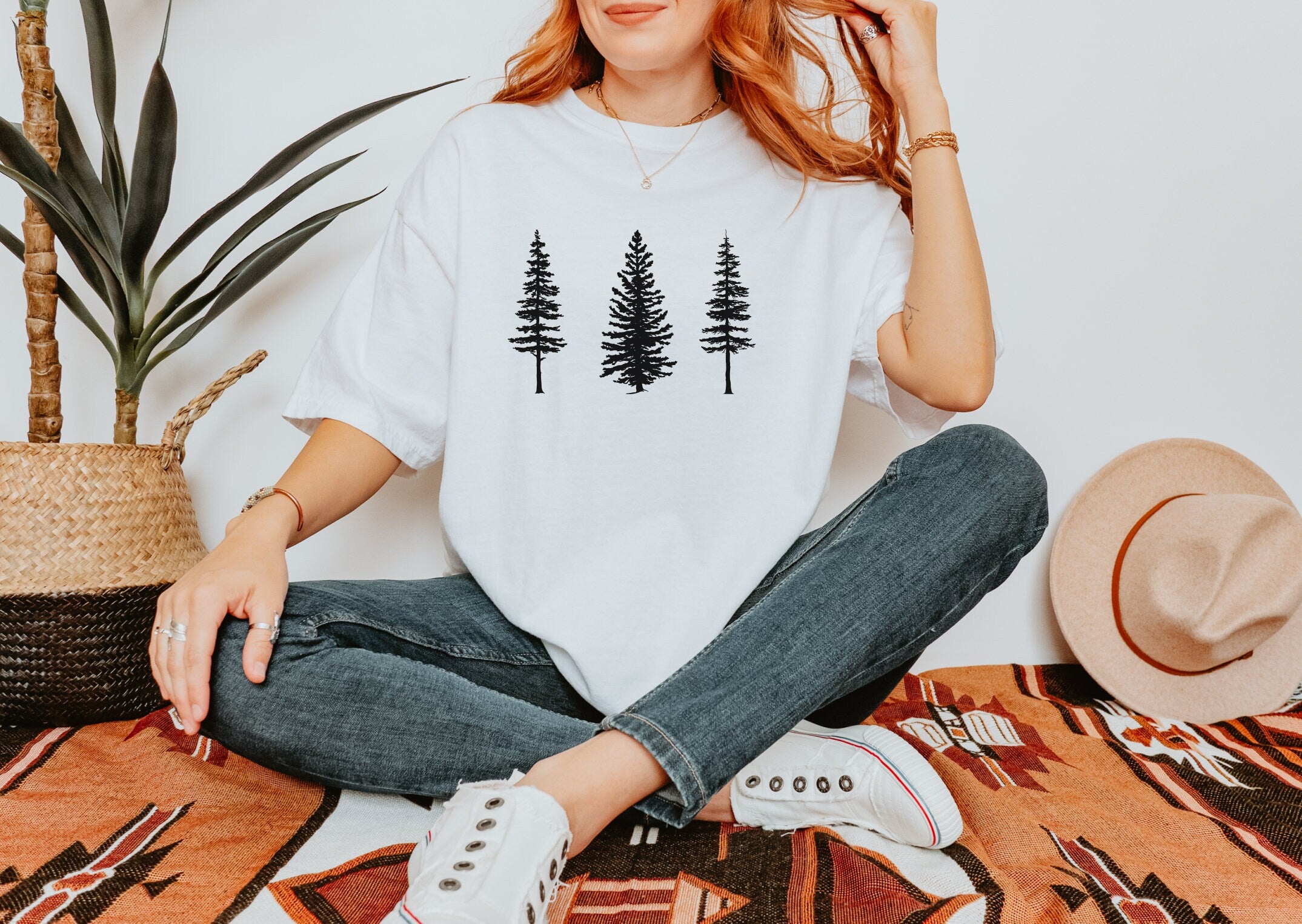 a woman sitting on the floor wearing a t - shirt with trees on it