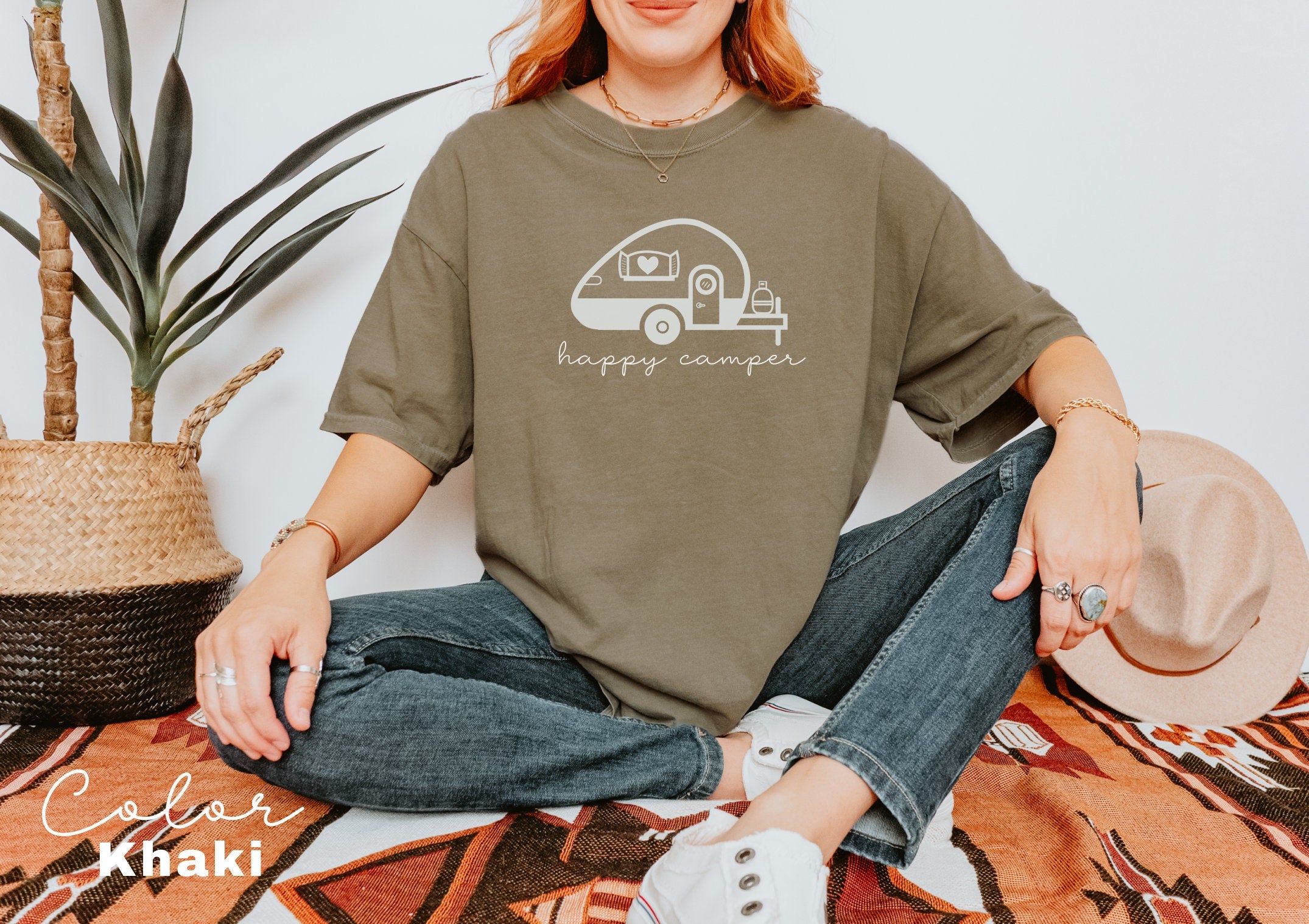 a woman sitting on the floor wearing a happy camper t - shirt