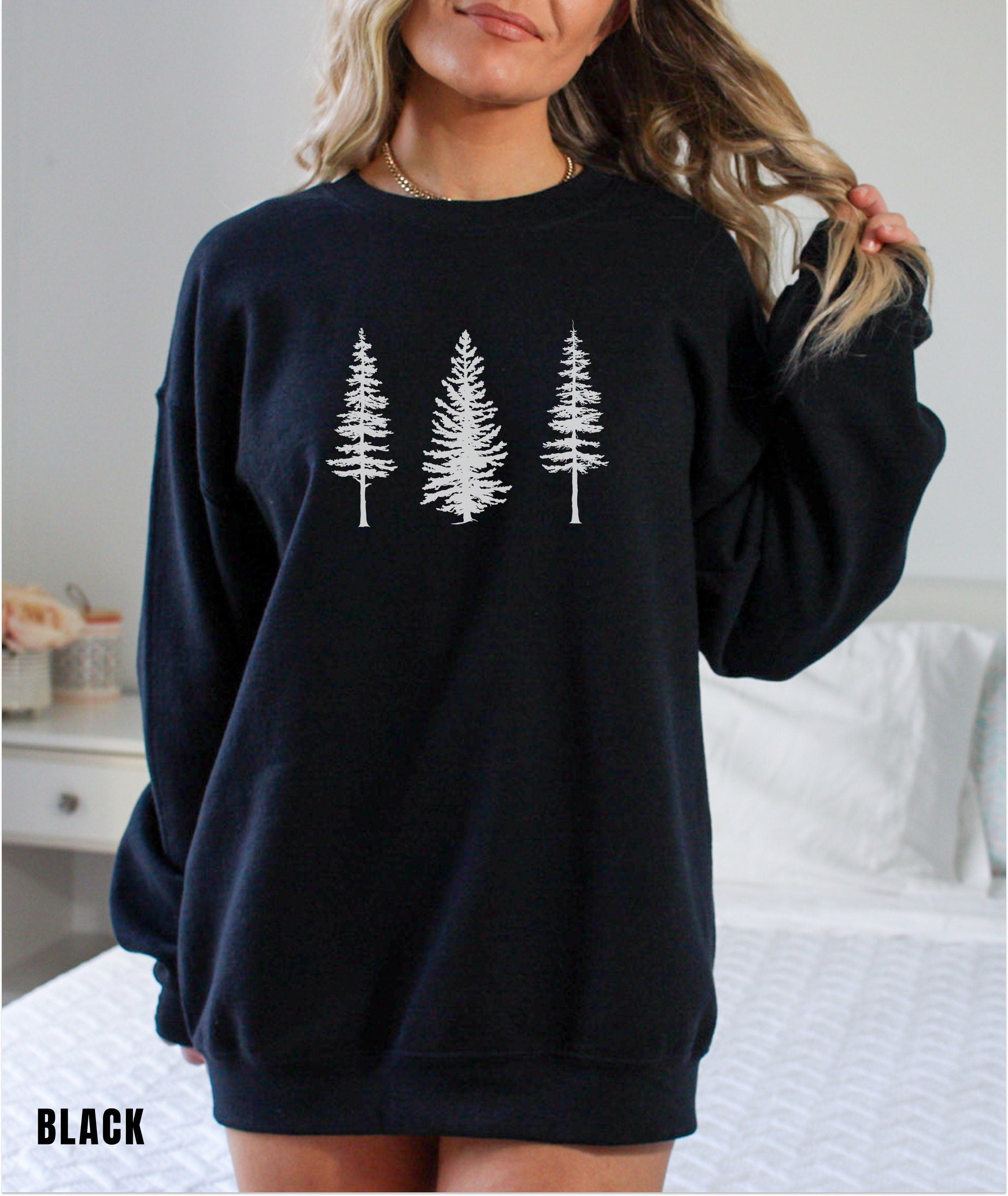 a woman wearing a black sweatshirt with white trees on it