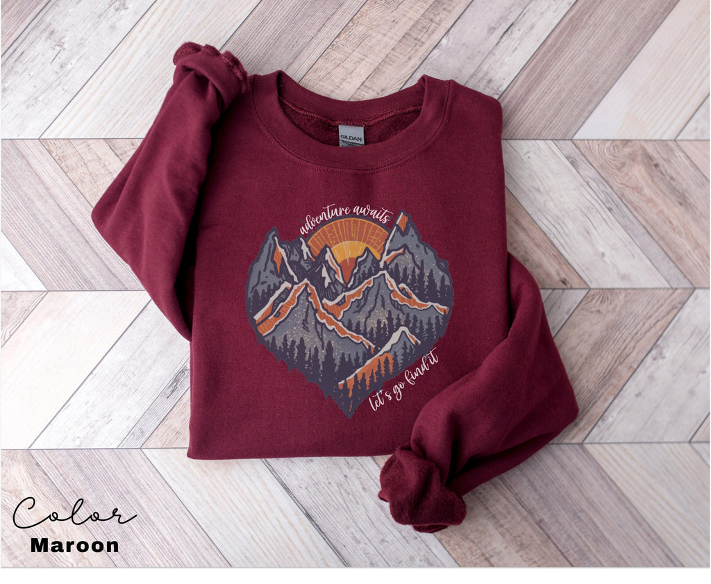 a maroon sweatshirt with a mountain scene on it
