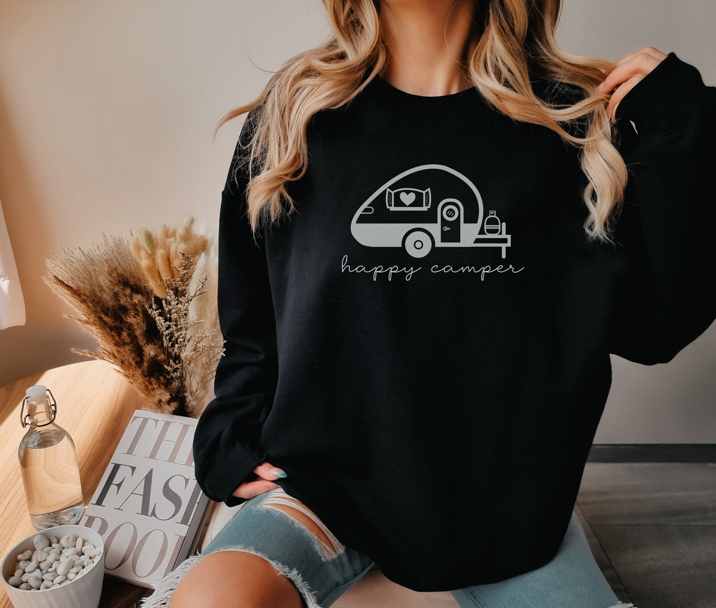 a woman wearing a black happy camper sweatshirt