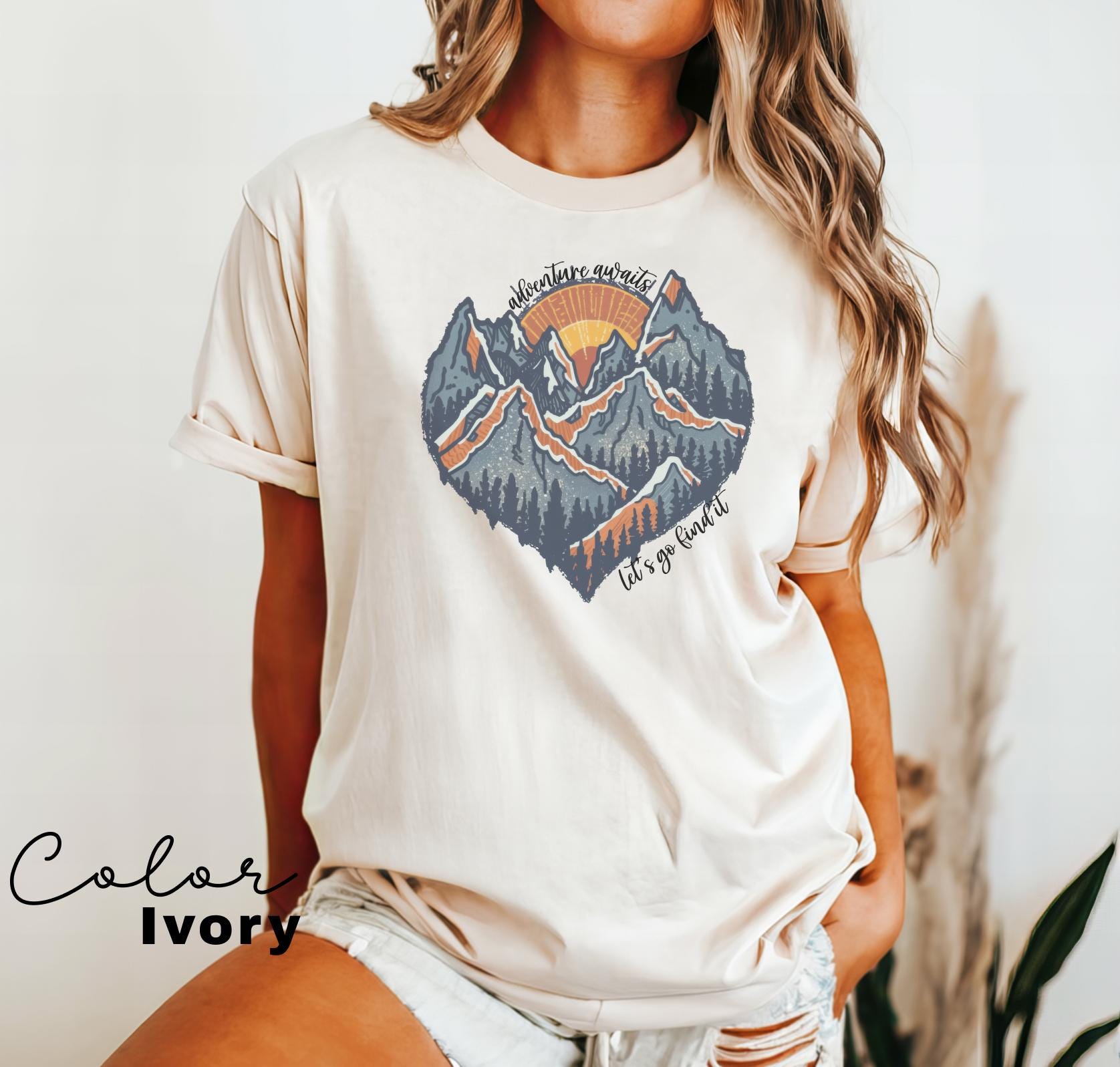 a woman wearing a white t - shirt with a mountain scene on it