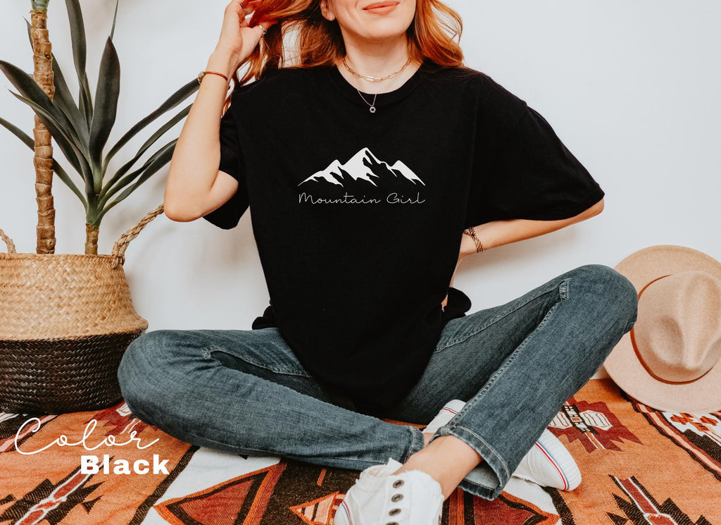 a woman sitting on the floor wearing a black mountain t - shirt