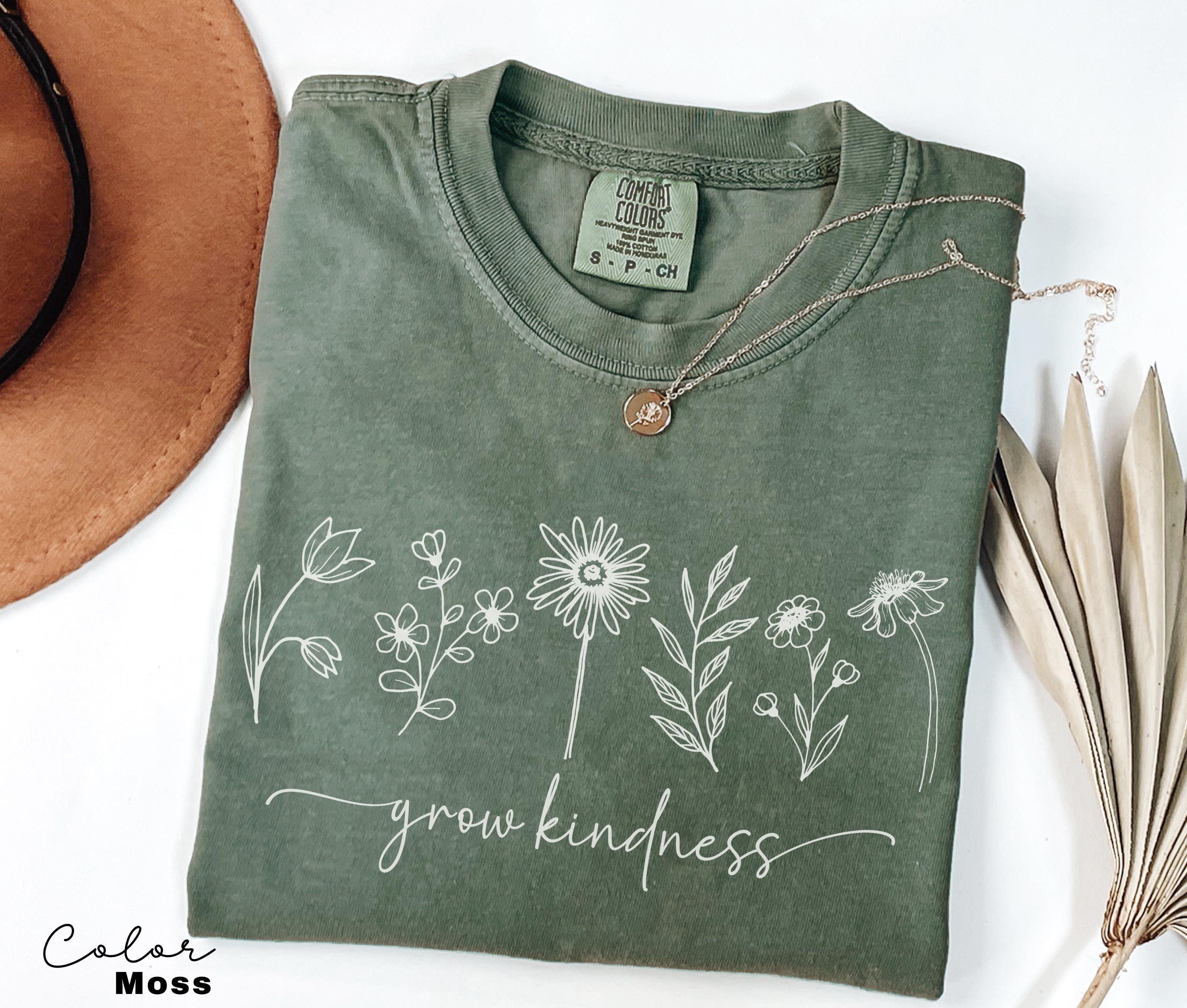 a t - shirt that says grow kindness next to a hat