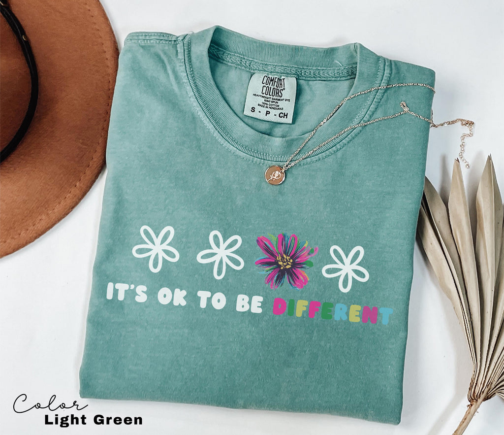 a t - shirt that says it's ok to be different next to a