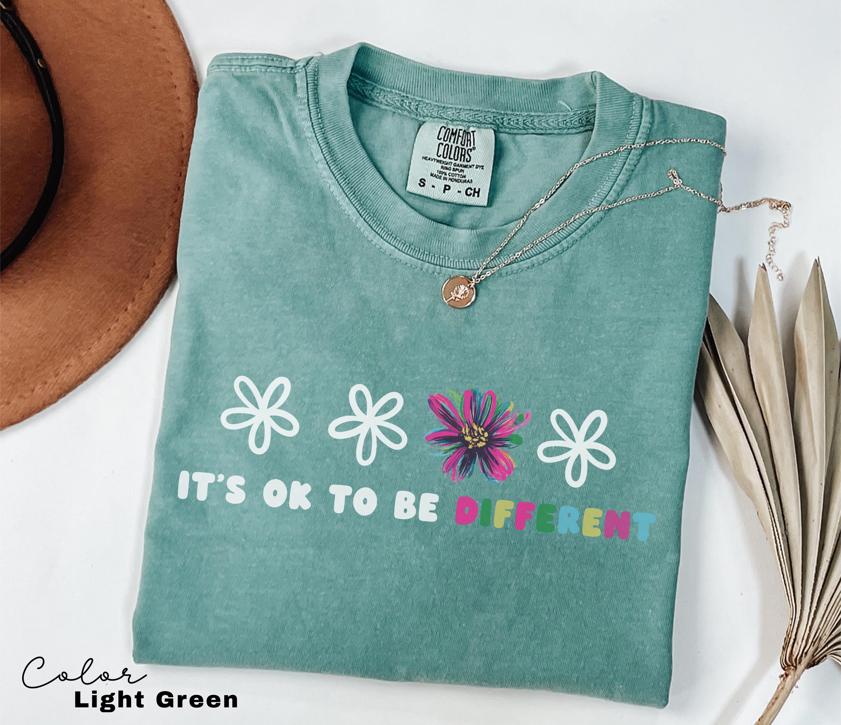 a t - shirt that says it's ok to be different next to a