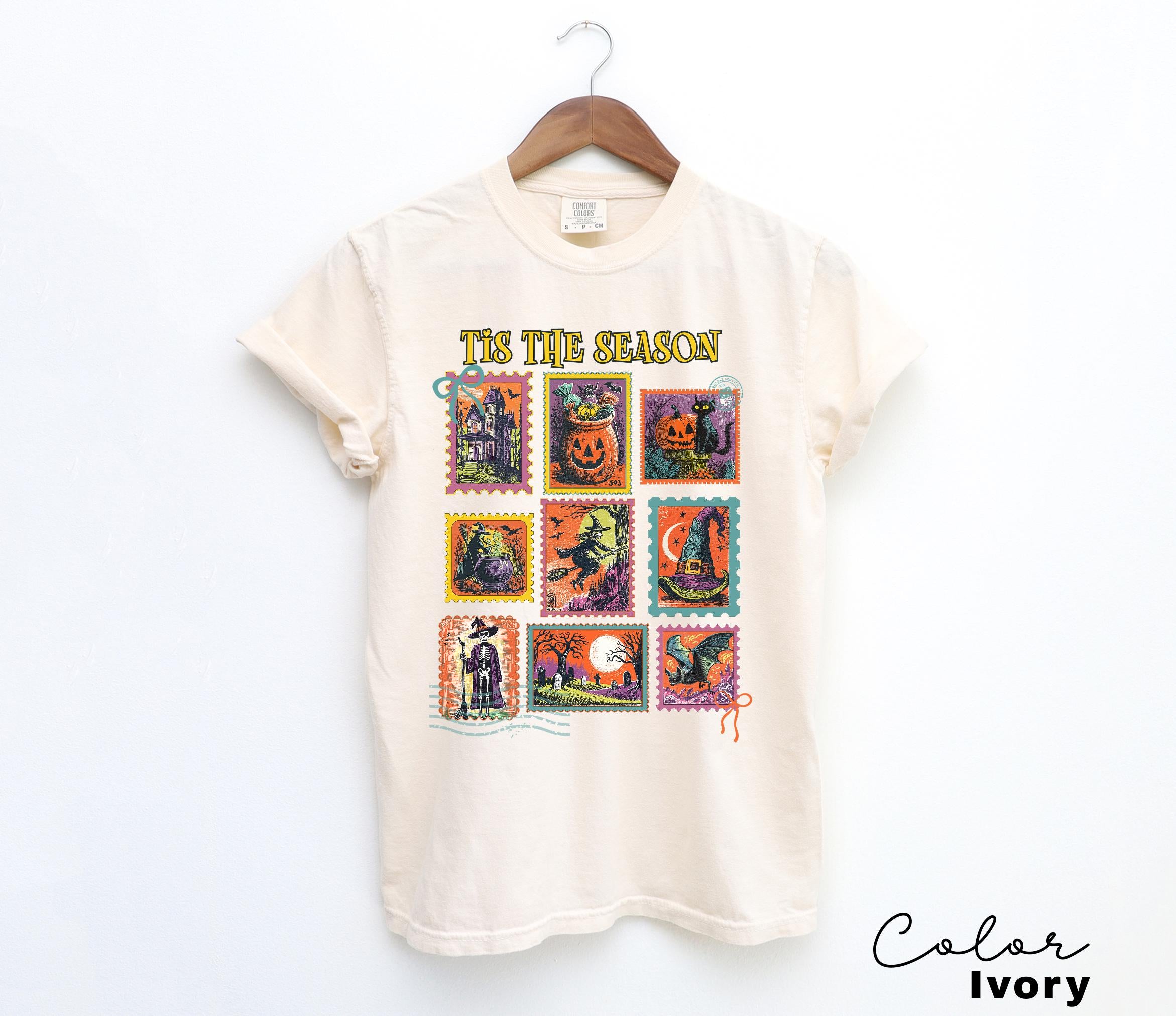 A white t-shirt with a graphic design featuring a collection of Halloween-themed stamps.