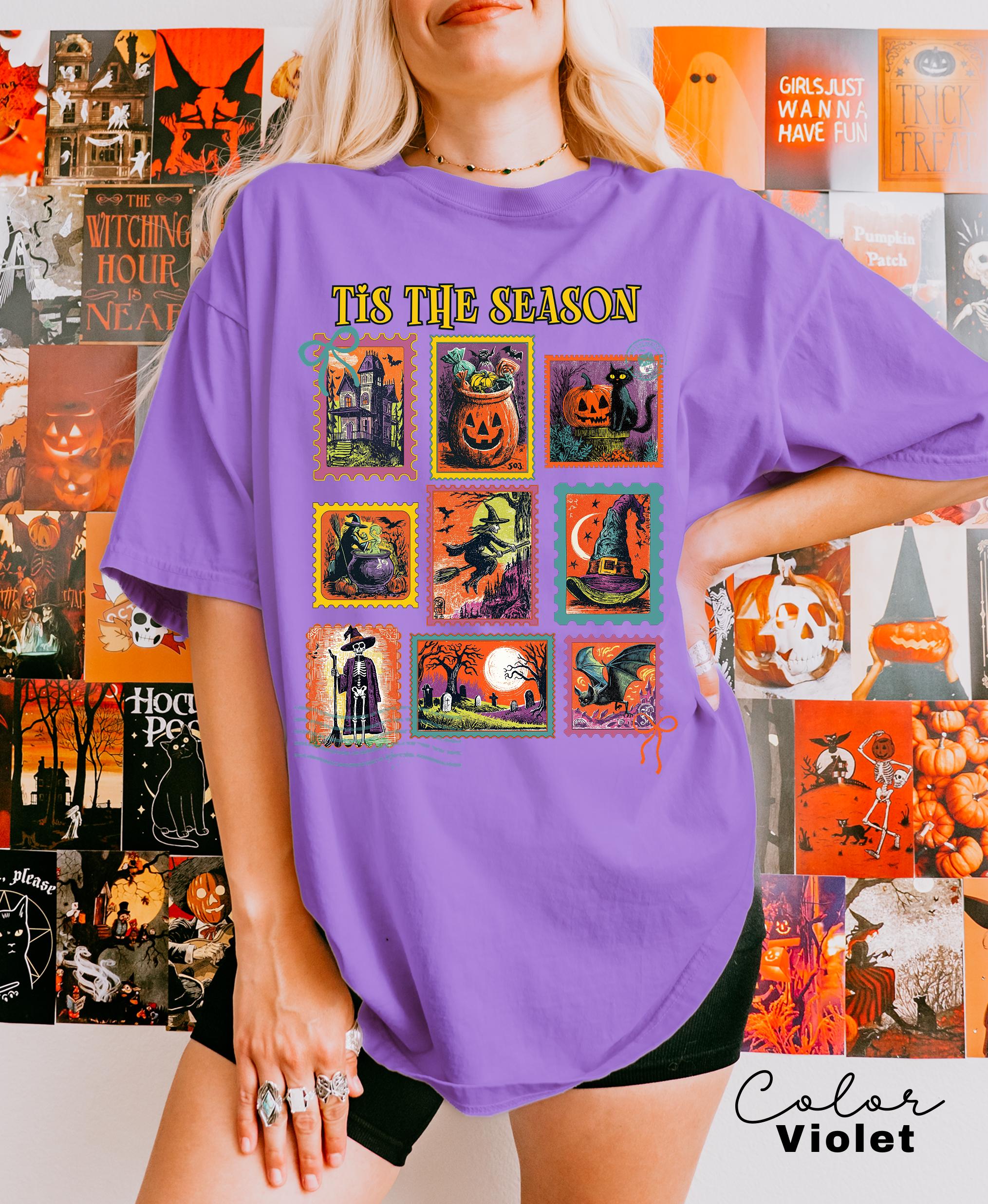 A woman wearing a purple t-shirt with a collage of Halloween-themed illustrations, including jack-o-lanterns, bats, skulls, and other spooky and festive images.