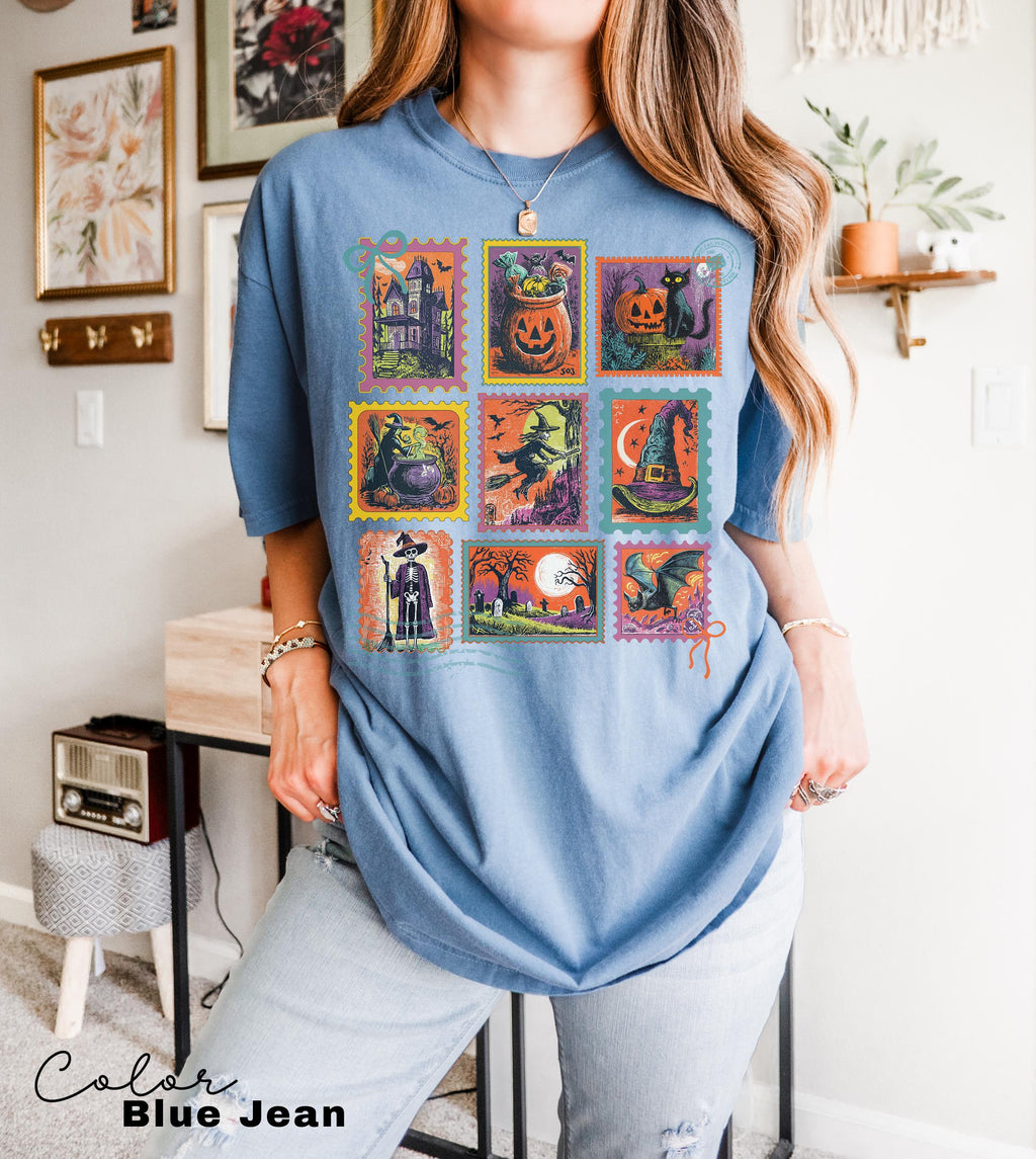 A woman wearing a blue t-shirt with a collage of Halloween-themed illustrations, including a jack-o-lantern, bats, a witch, a pumpkin, and other spooky and festive images.