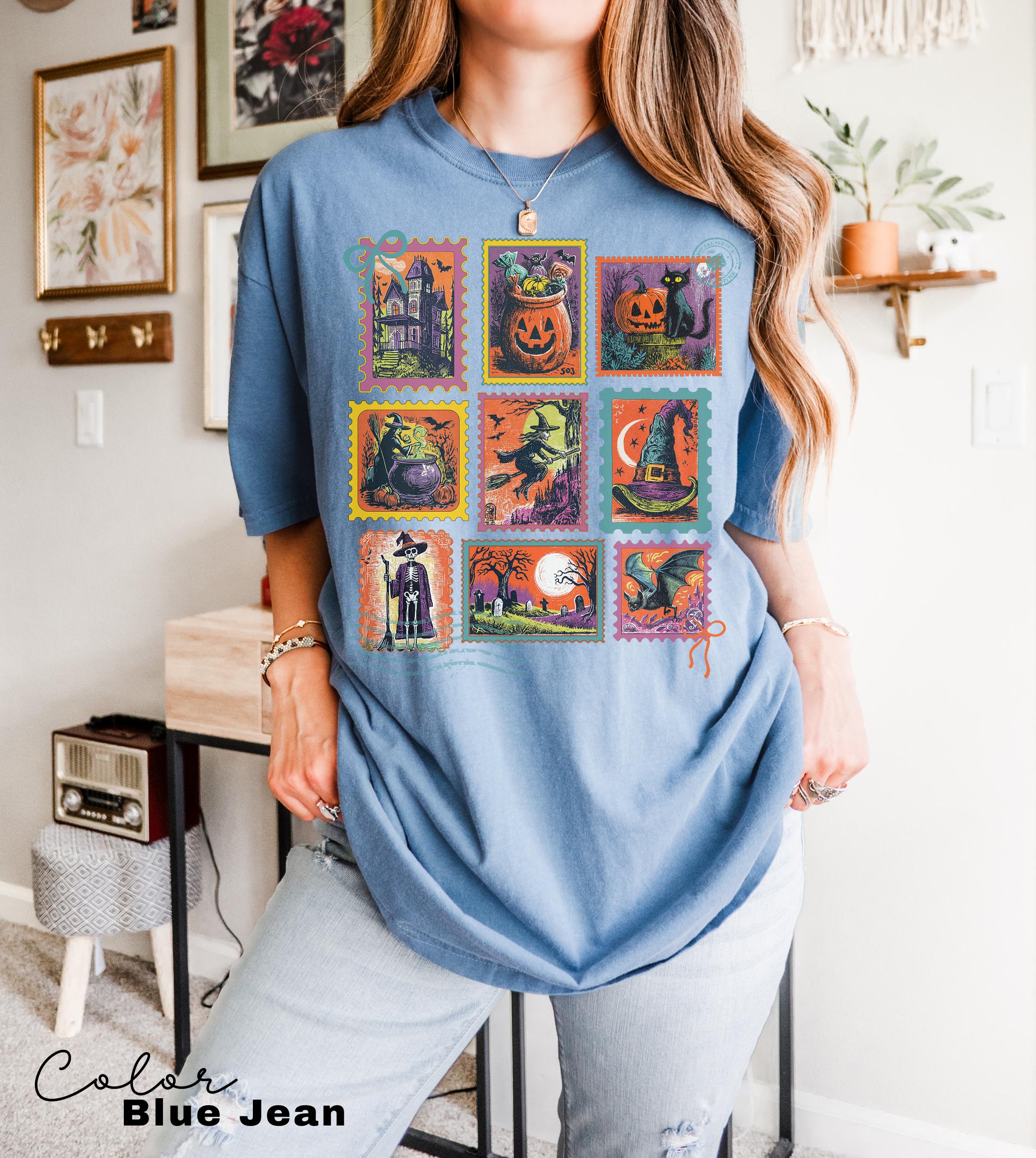 A woman wearing a blue t-shirt with a collage of Halloween-themed illustrations, including a jack-o-lantern, bats, a witch, a pumpkin, and other spooky and festive images.