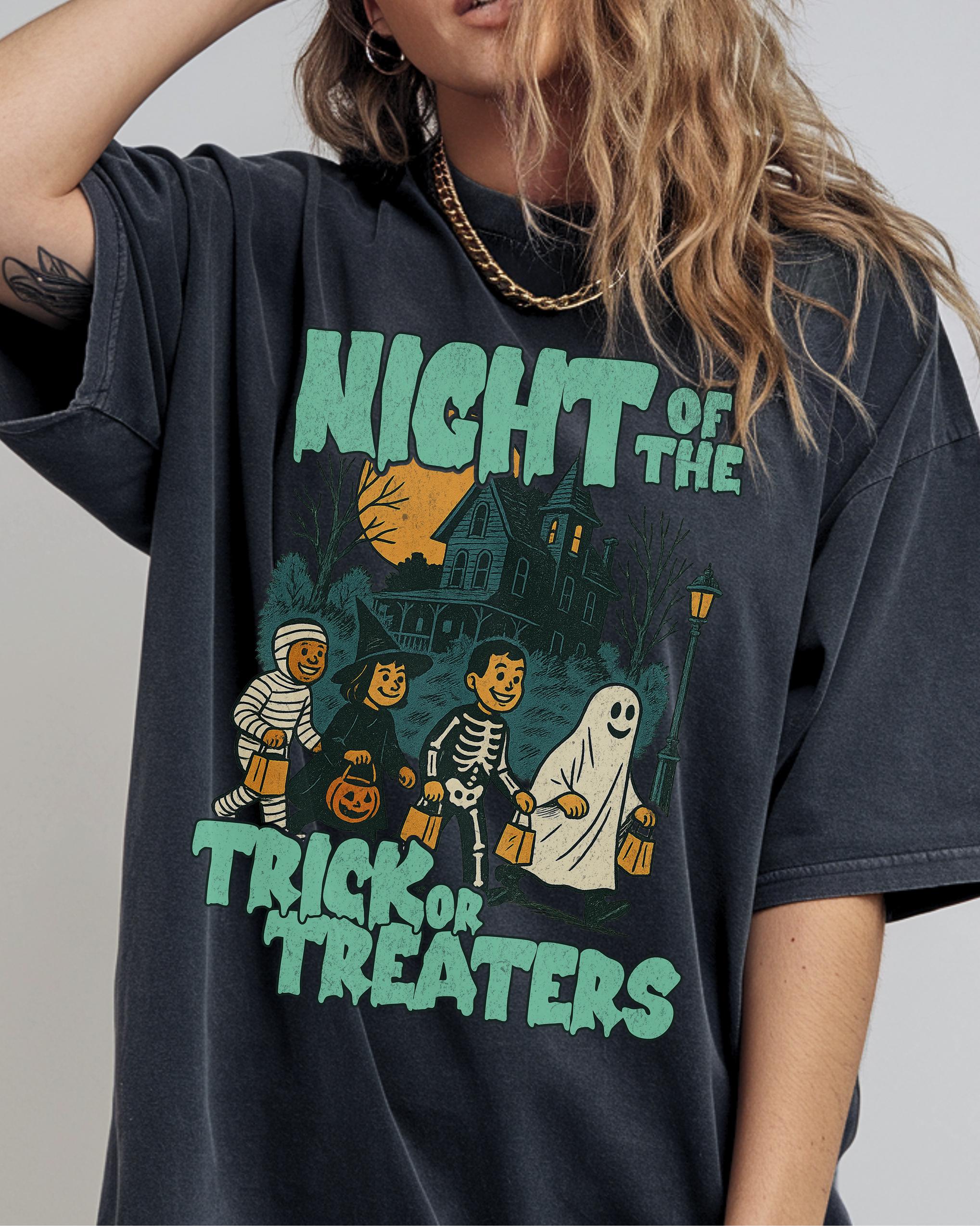 A person wearing a black t-shirt with a graphic design depicting a skeleton, ghost, and Halloween-themed elements.