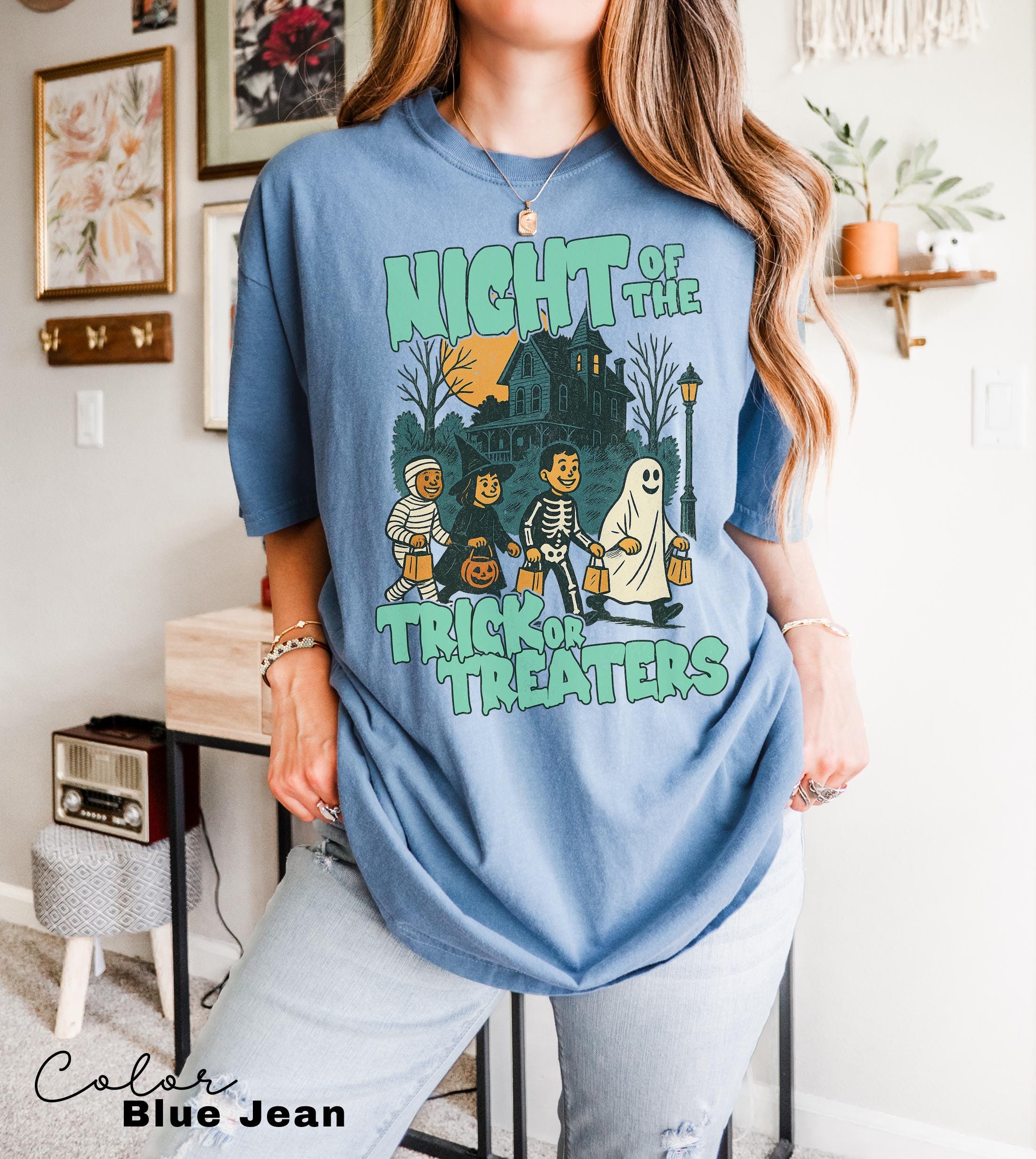 A woman wearing a blue t-shirt with a graphic design depicting a skeleton and ghost, along with the text "Night of the Trick or Treaters".